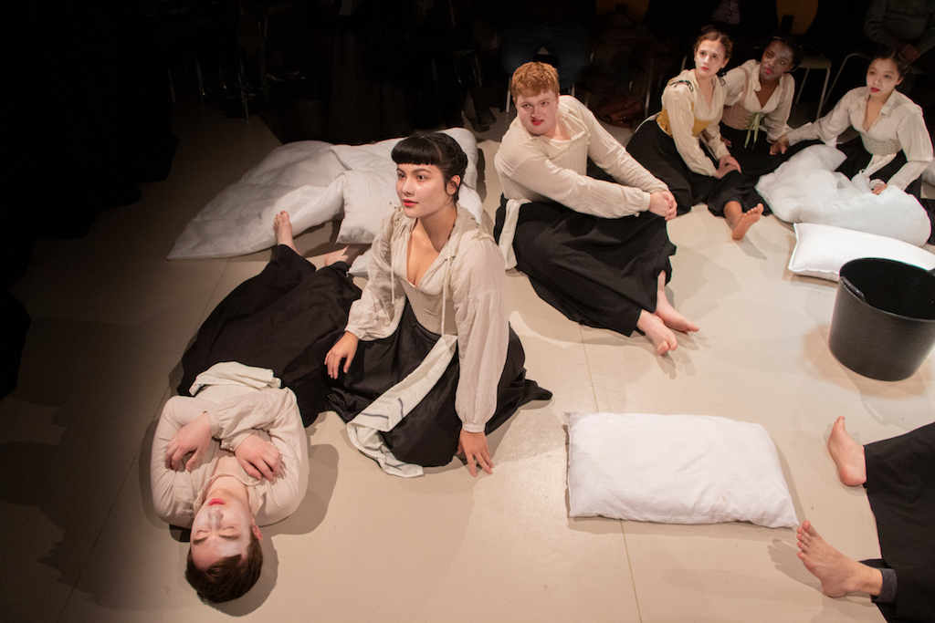 Students sitting and lying on stage, performing Macbeth.